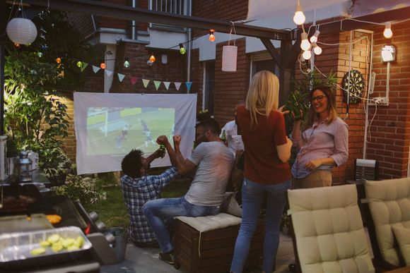 Personen bei einer Gartenparty mit Leinwand